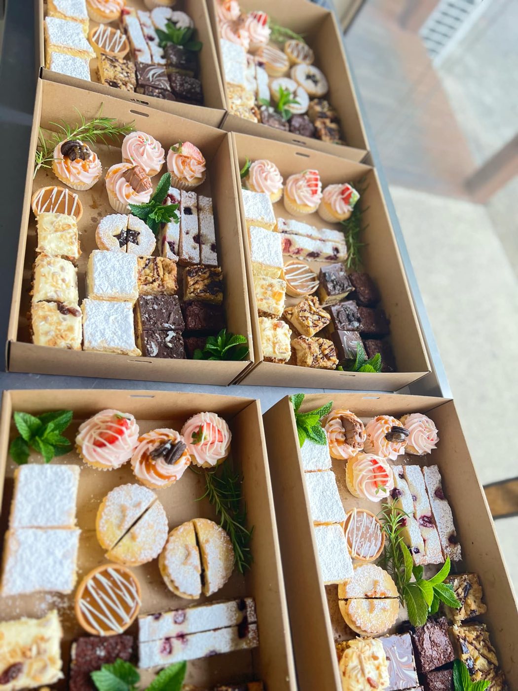 Cardboard boxes filled with slices, tarts and small decorated cakes